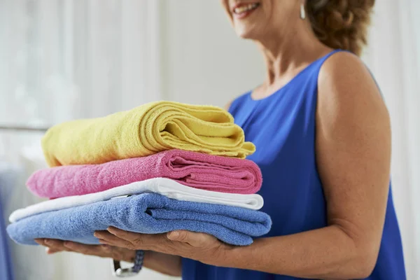 Starsza Kobieta Przewożąca Kolorowe Czyste Ręczniki Rękach Prasowaniu — Zdjęcie stockowe