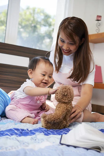 年轻的越南妇女和她的小女儿在床上玩玩具 — 图库照片