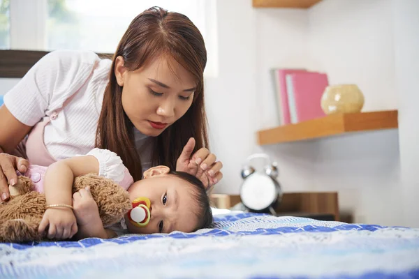 Joven Madre Asiática Mirando Pequeña Hija Descansando Cama Con Chupete — Foto de Stock