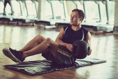 Fit yakışıklı genç adam tıp topu ile yan katlanmış yapıyor