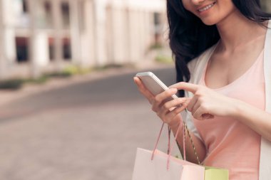 Akıllı telefonu tutan ve alışveriş merkezinde mevsimlik satış hakkında arkadaşlarına mesaj alan kadının elleri