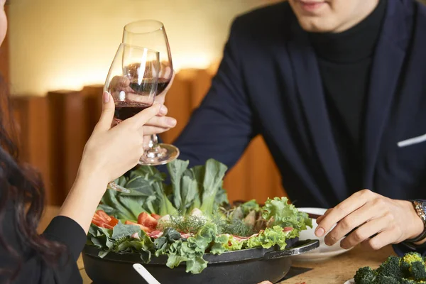 テーブルの上にワイングラスとグリーンサラダの食事とデートのカップル — ストック写真
