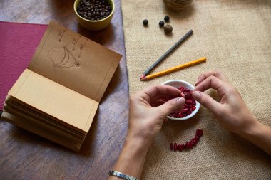 Kitaptaki talimatlara göre taşlardan kolye yapan kadının yakın çekim