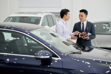 Orta yaşlı Asyalı adam satış müdürü yardımıyla yeni araba satın alma