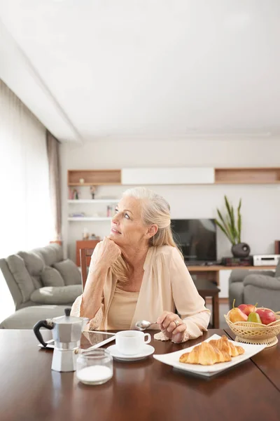 自宅でコーヒーとクロワッサンと朝食を食べる夢の先輩女性 — ストック写真