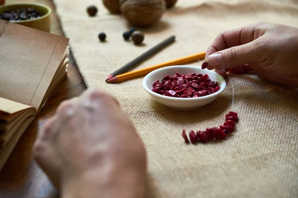 Close Van Vrouw Maken Armband Van Natuurlijke Rode Stenen Aan — Stockfoto