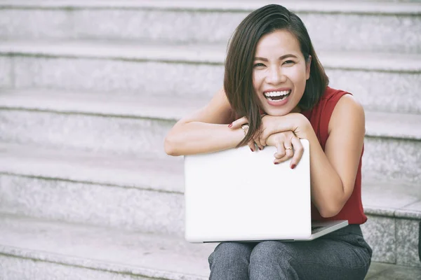 그녀의 무릎에 노트북계단에 카메라 야외에서 웃고있는 아시아 여성의 초상화 — 스톡 사진
