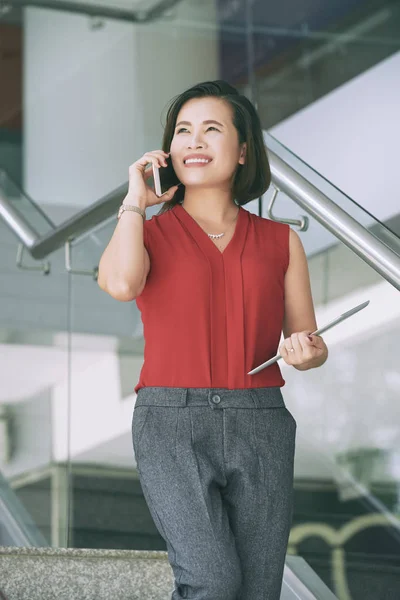 アジアの女性リーダーがタブレットPcを持って階段を歩き 現代のオフィスで携帯電話で話す — ストック写真