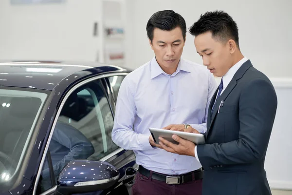 Mladý Vietnamský Car Dealership Manager Zobrazující Informace Tabletu Počítače Klientovi — Stock fotografie