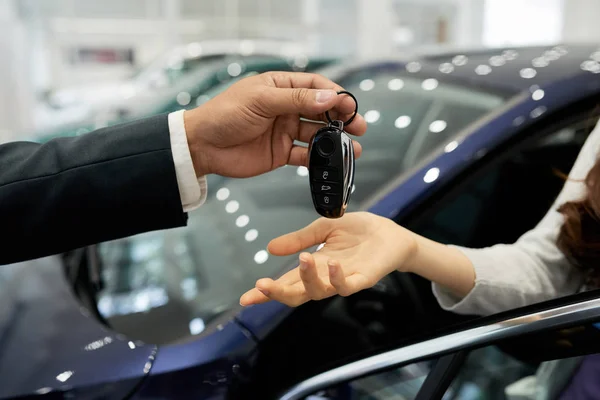 Dealership salesman giving electronic car keys to female customer