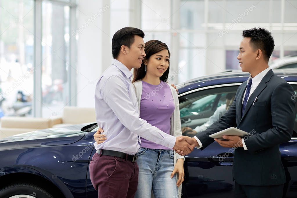 Salesman shaking hand of customer who came in dealership to buy a car for his wife