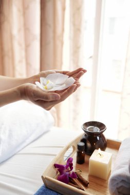 Mum ve uçucu yağ ile tepsi üzerinde güzel çiçek ile kadın Eller