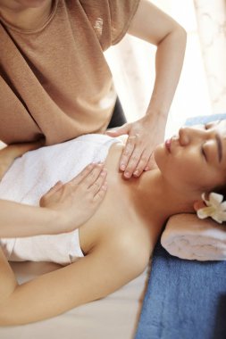 Cosmetologist gençleştirici yağlar ile genç Asyalı kadının göğüs ve boyun masaj