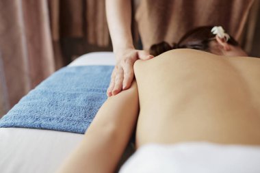 Masörler spa salonunda genç kadının ince sırtına el attı
