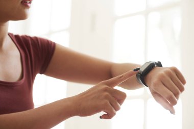 Evde egzersiz yaparken nabzı kontrol eden genç kadının elleri