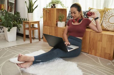 Pretty Vietnamlı kız öğrenci taze olgun kırmızı elma yeme ve odasında dizüstü bilgisayar üzerinde çalışıyor