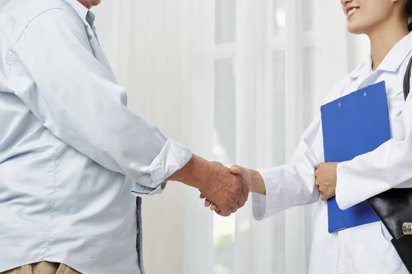 Primer Plano Joven Doctora Sonriente Estrechando Mano Paciente Mayor Mientras —  Fotos de Stock