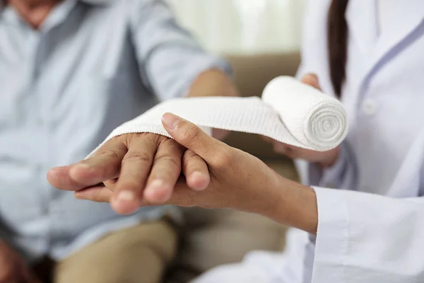 Zbliżenie Kobiecego Lekarza Kładąc Bandaż Uszkodzoną Rękę Starszego Mężczyzny Szpitalu — Zdjęcie stockowe