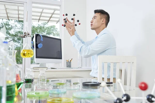 亚洲大学生坐在桌旁 在实验室中考察分子模型的结构 — 图库照片