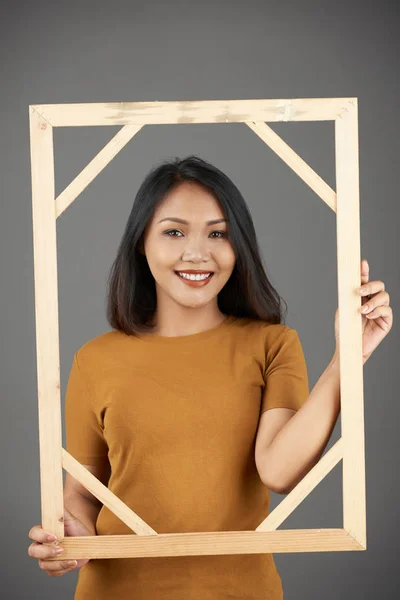 漂亮的微笑的年轻亚洲妇女与木框架摆姿势的肖像 — 图库照片