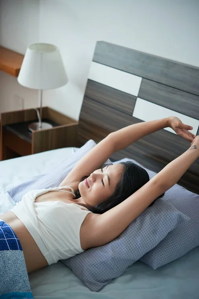 Молодая Женщина Лежит Кровати Растягиваясь После Сна Улыбаясь Спальне Дома — стоковое фото