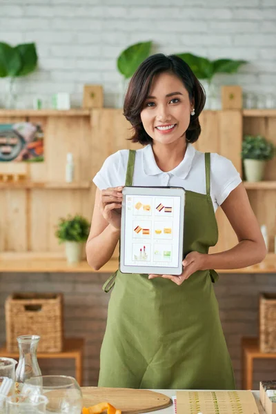 Asian Smiling Woman Green Apron Holding Catalog Different Cosmetic Shower — Stockfoto