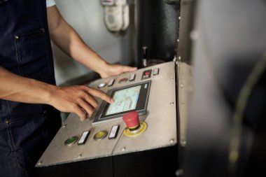Erkek operatör bilgisayar makinesinin ekranına dokunmanın ve fabrikadaki üretim sürecinin kontrol altına alınmasının yakın çekim