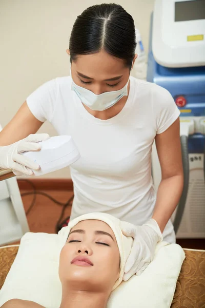 亚洲漂亮女人躺在闭着眼睛 在美容院接受激光治疗她的脸 — 图库照片