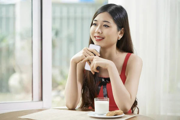 Jonge Aziatische Vrouw Zitten Aan Tafel Met Mobiele Telefoon Denken — Stockfoto