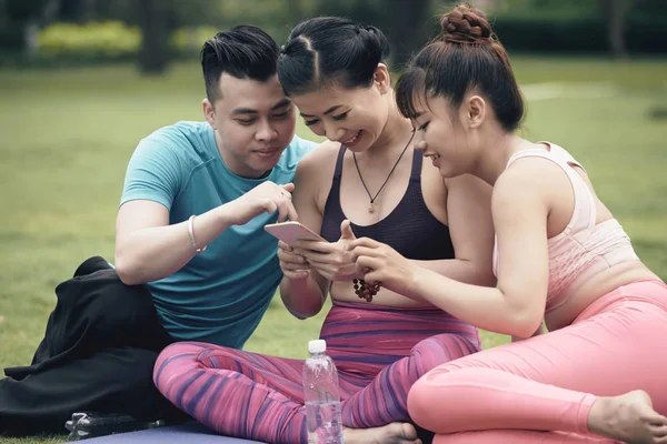 Group of cheerful Asian people watching on smartphone screen