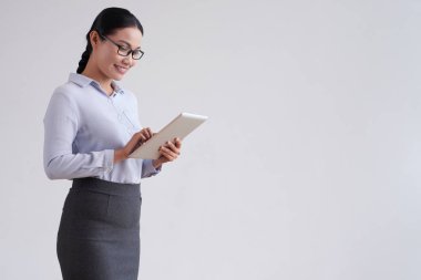 Gülümseyen güzel iş kadını ayakta gözlük giyen ve beyaz arka plan üzerinde dijital tablet kullanarak online iletişim