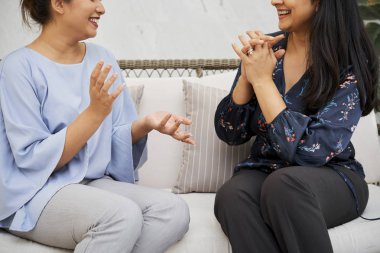 Kanepede gülümseyerek oturan ve işlerini tartışıyor zarif giyimli iki iş arkadaşı