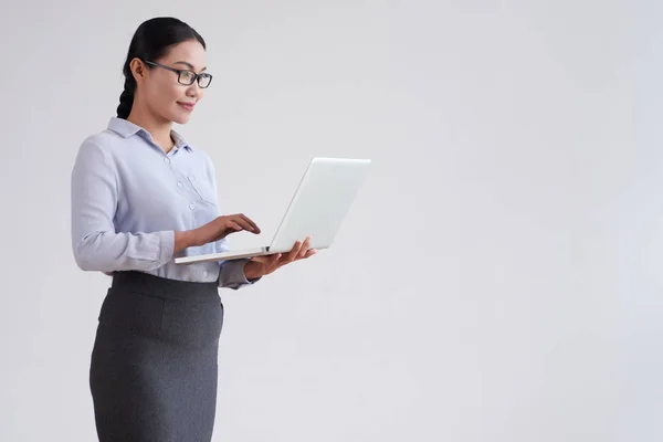 戴眼镜的年轻亚洲女商人站在电脑前上网工作 电脑是白色背景的 — 图库照片