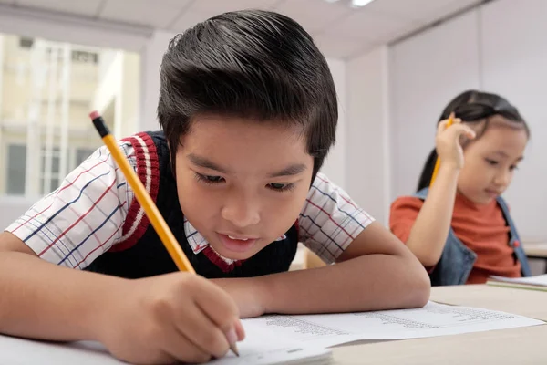 Asiatischer Schüler Sitzt Schreibtisch Und Schreibt Notizbuch Mit Bleistift Hintergrund — Stockfoto