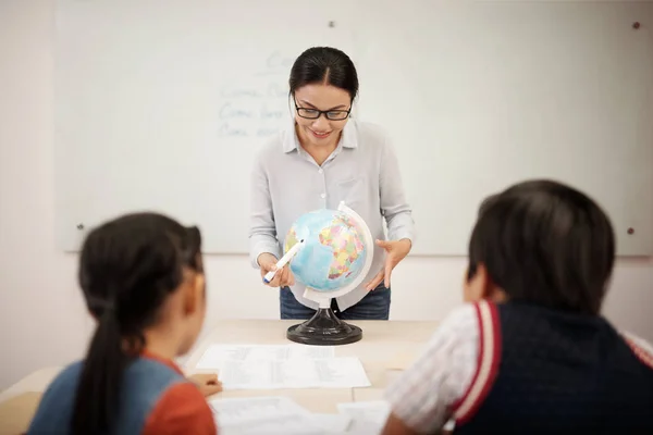 Gülümseyen Genç Öğretmen Dünyayı Işaret Ediyor Sınıftaki Öğrencilere Coğrafyayı Anlatıyor — Stok fotoğraf
