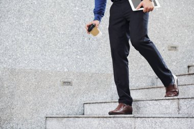 Sabah kahvesi ve dijital tabletle genç girişimci ofise ya da toplantıya koşuyor