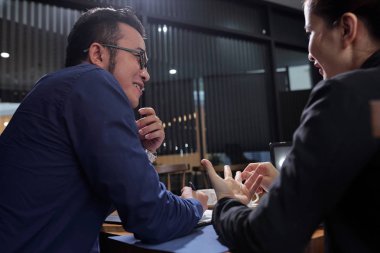 Gülümseyen Asyalı işadamı onun kadın iş arkadaşı yeni yeni fikirler dinlerken notlar alarak