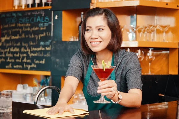 彼女の手においしいカクテルでカウンター表面を拭く魅力的な笑顔ベトナムのバーテンダー — ストック写真