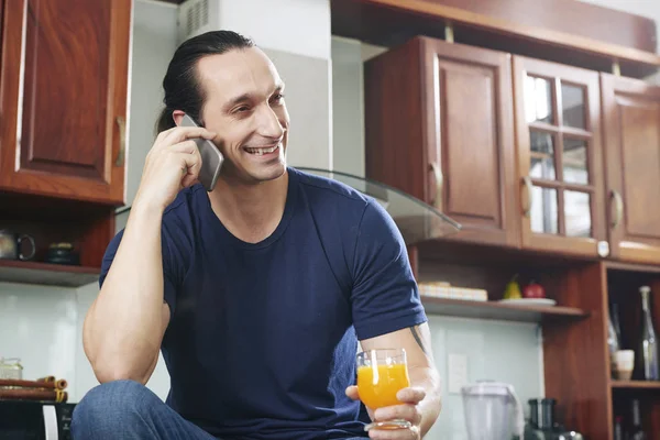 Uomo Sorridente Seduto Tenendo Succo Arancia Mano Ridendo Durante Telefonata — Foto Stock