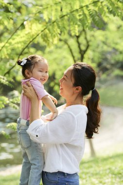 Anne onun küçük gülümseyen kızı kaldırma ve sonsuz sevgi ile ona bakıyor