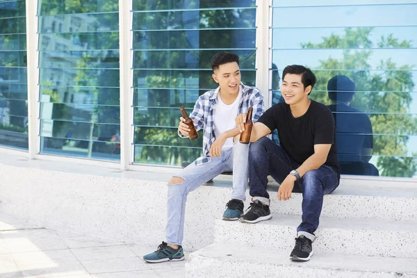 Dwóch Azjatyckich Nastolatków Siedzi Pobliżu Nowoczesnego Szkła Budynku Picia Piwa — Zdjęcie stockowe