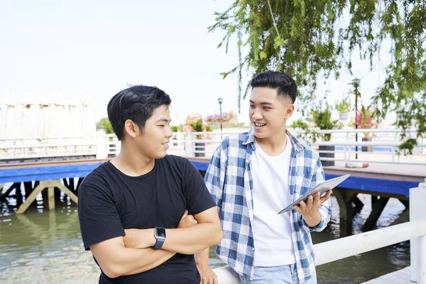 两个微笑的青少年使用数字平板电脑 并讨论的东西 而站在码头户外 — 图库照片