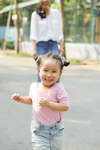 快乐可爱的小女孩运行 她的母亲站在背景 — 图库照片