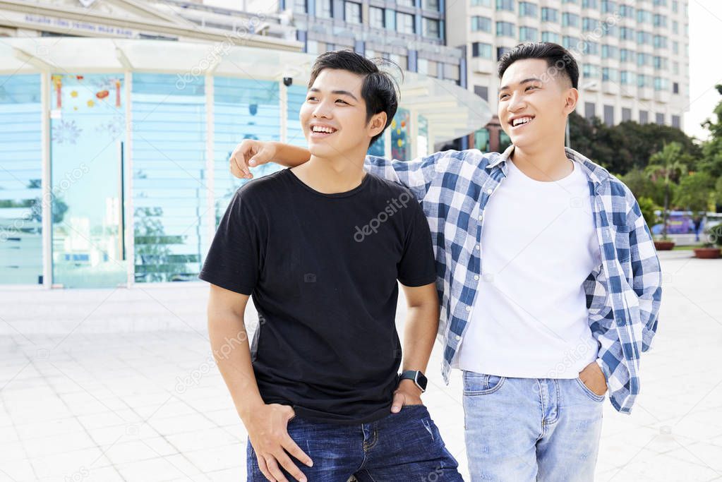 Two Asian happy friends walking in the city together and enjoying their meeting