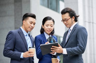 Şehirde dururken dijital tablette çevrimiçi projeyi ekip halinde tartışan iş adamları 