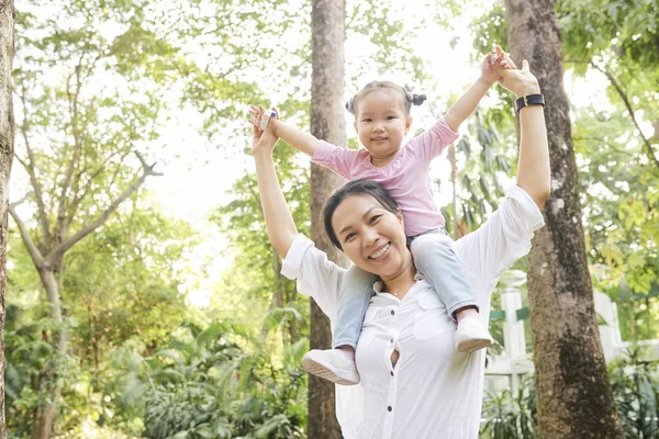 幸せなアジアの女性は 娘にピギーバックライドを与え 喜びを表現するために手を上げ — ストック写真