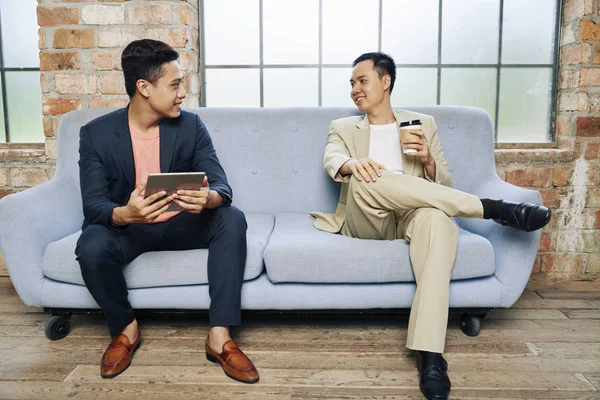 Jovens Empresários Confiantes Sentados Sofá Seu Escritório Discutindo Seus Negócios — Fotografia de Stock