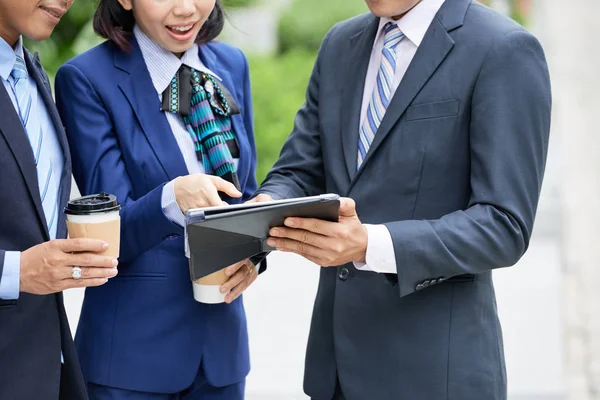 디지털 태블릿을 가리키고 야외에서 서있는 온라인 프리젠 테이션을 논의하는 공식적인 — 스톡 사진