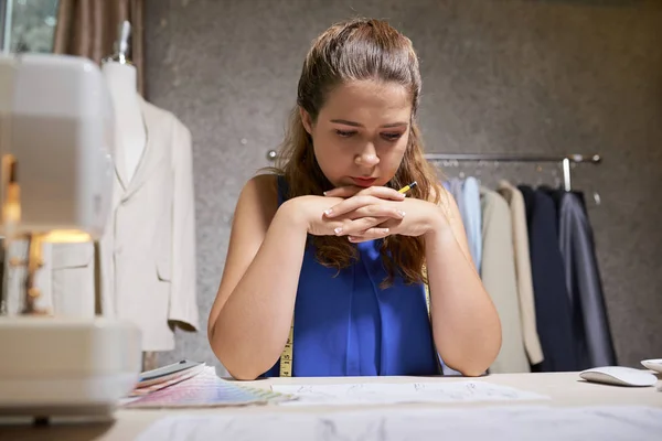 Serious Tailor Sitting Table Looking Her Sketches Thinking New Clothes — Stock Photo, Image