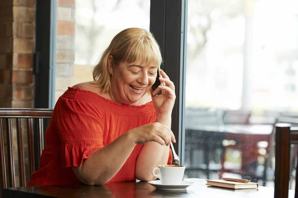 Счастливая Зрелая Женщина Смешивает Сахар Кофе Разговаривает Телефону — стоковое фото